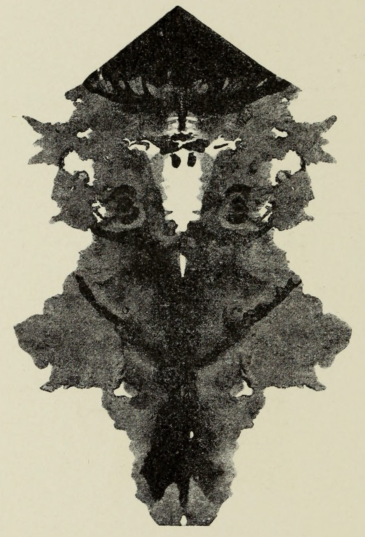 A dark symmetrical figure under a black pointed cap, a pale face and two round eyes in the blot