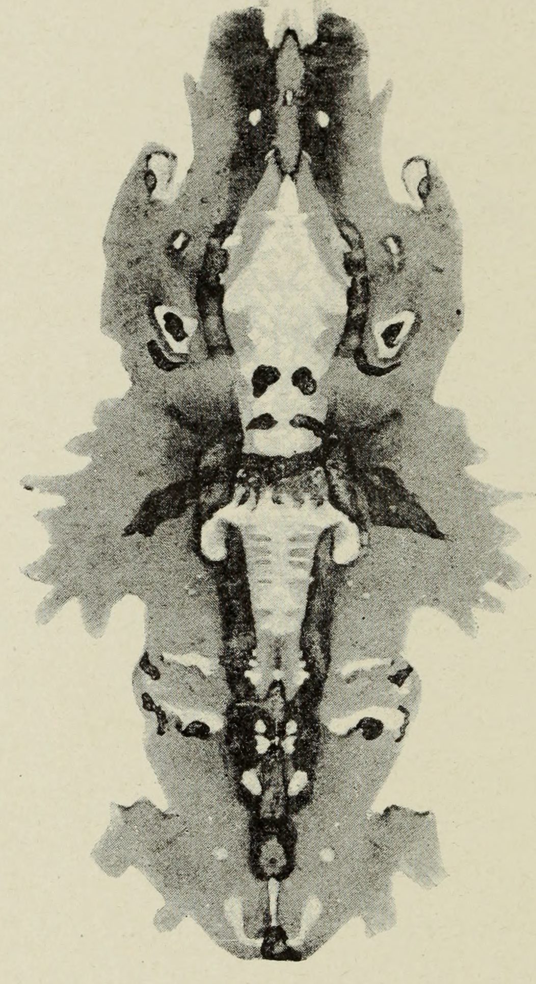 A long vertical figure with a skull at its centre and a second face below, grey wings spreading from it